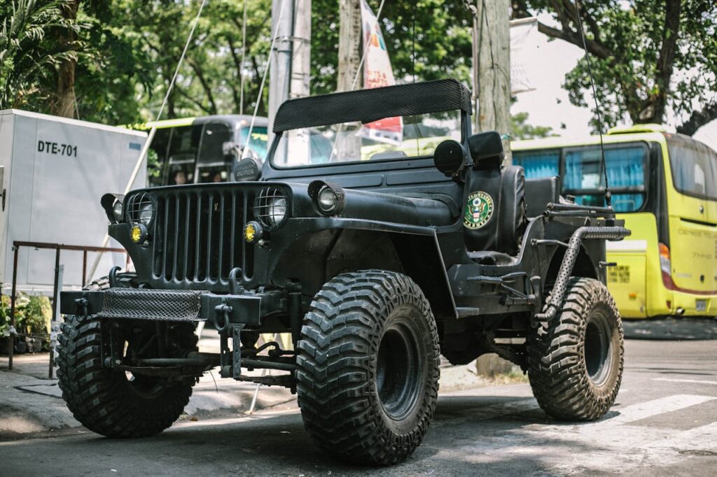 A classic vintage military jeep parked on a street under daylight.